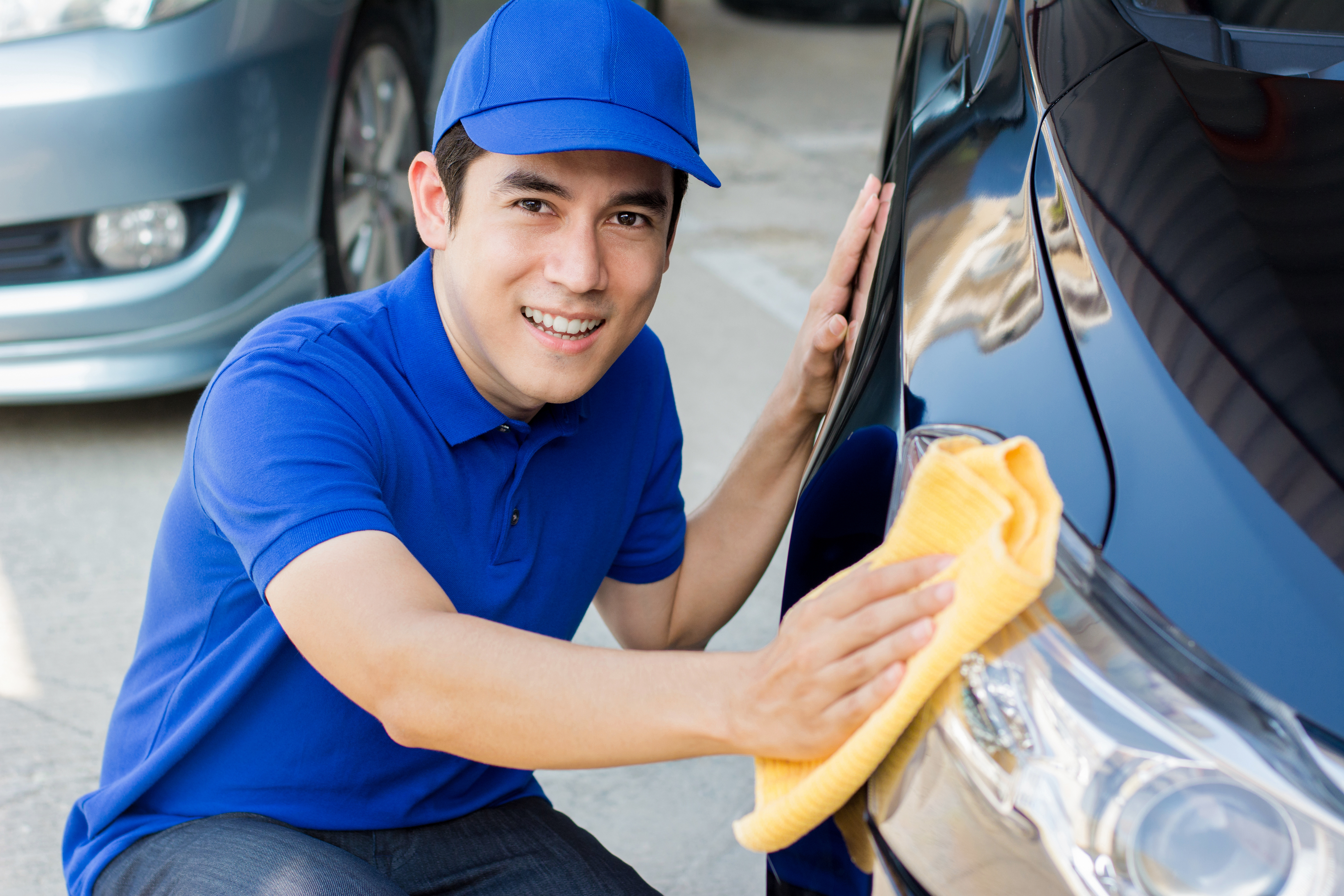 Young man polishing (cleaning) car with microfiber cloth